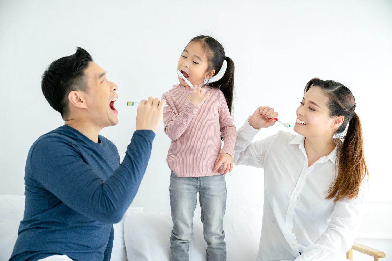 Happy family cleaning teeth with toothbrushes together